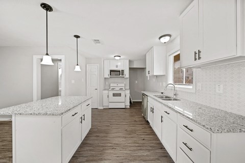 a white kitchen with marble counter tops and white cabinets