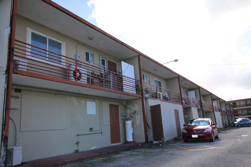 an apartment building with a red car parked outside