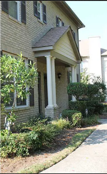A house with a front porch and a tree in front.