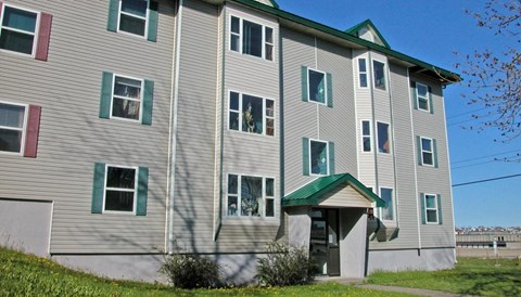 A grey building with green trim and a green roof.
