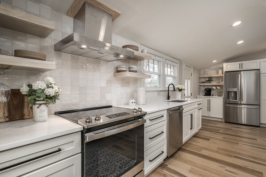 a large kitchen with white cabinets and stainless steel appliances