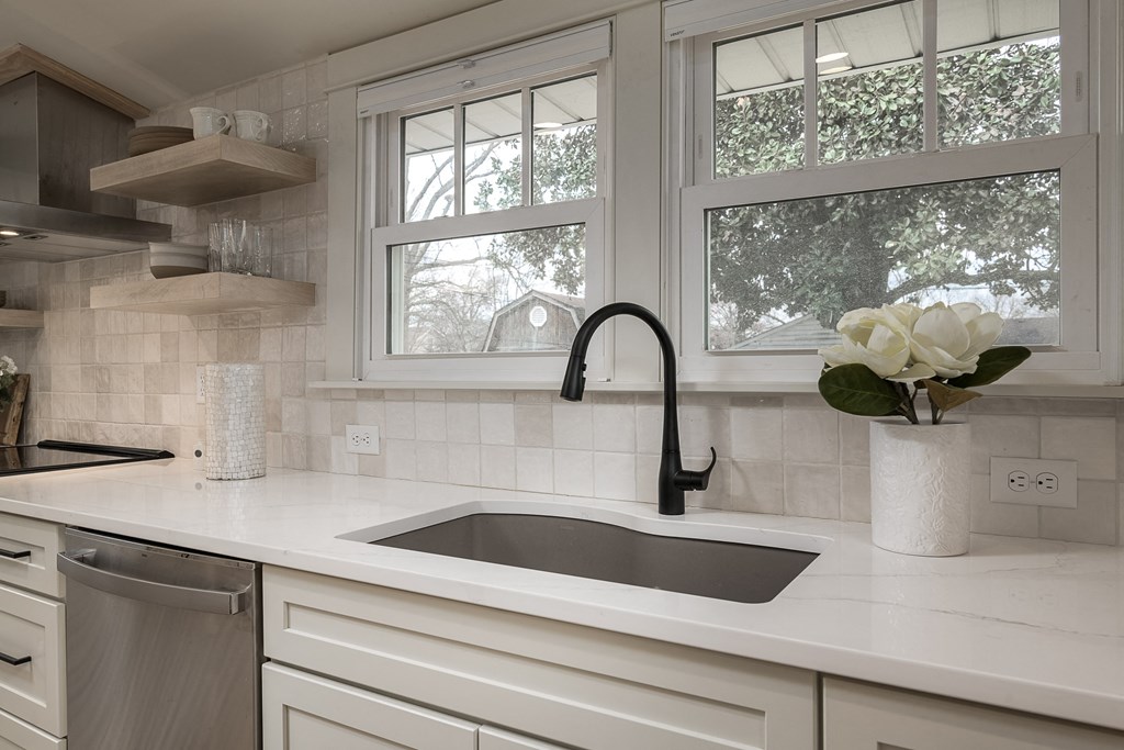 a white kitchen with a sink and a window