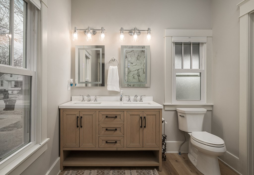 a bathroom with a sink toilet and mirror and a window