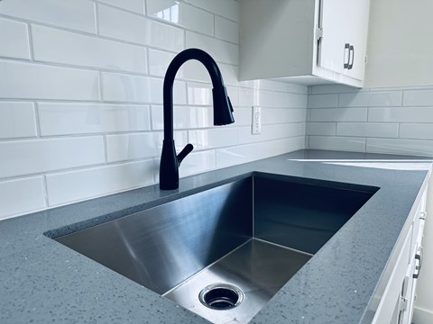 A modern kitchen with a stainless steel sink and a black faucet.