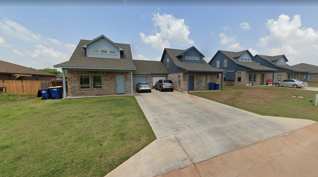 a house with a driveway and a yard with cars parked in front of it