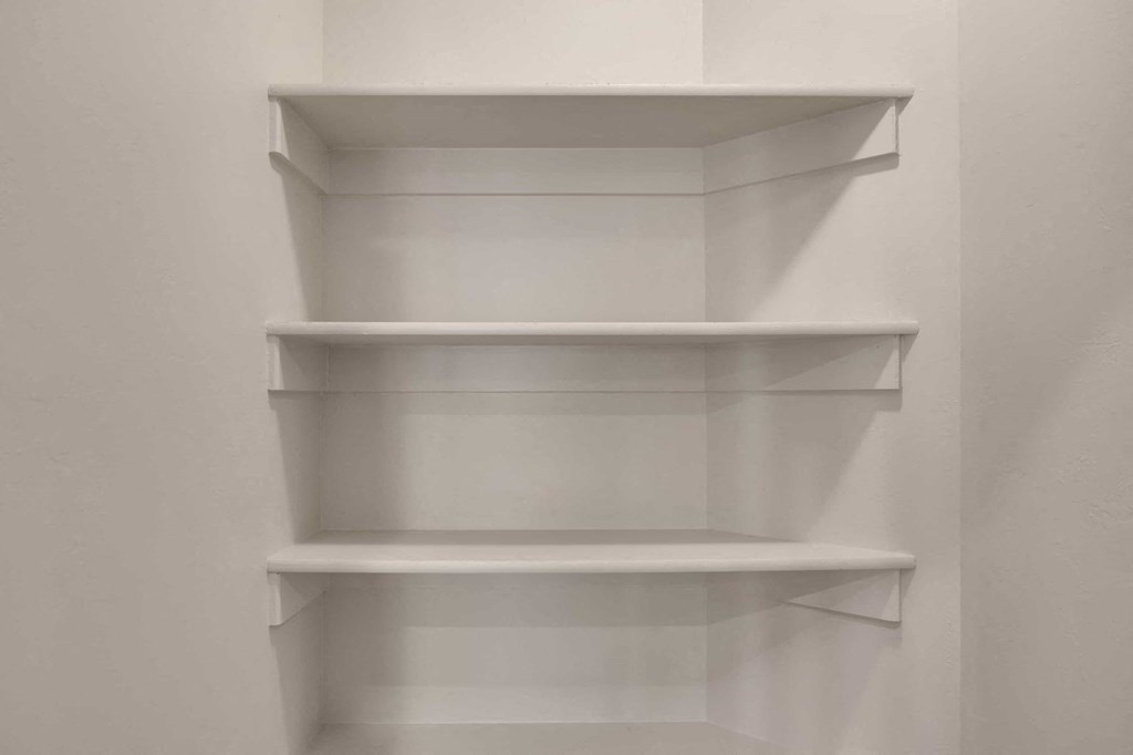 three empty white shelves on a wall in a room