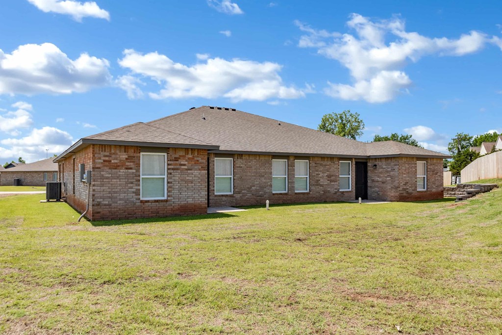 a brick house with a grassy yard and a cloudy sky