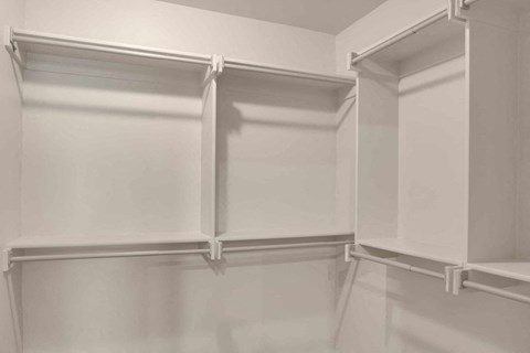 a walk in closet with white cabinets and white walls
