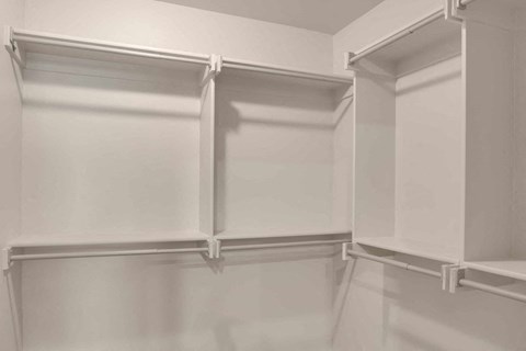 a walk in closet with white cabinets and white walls and a white closet door