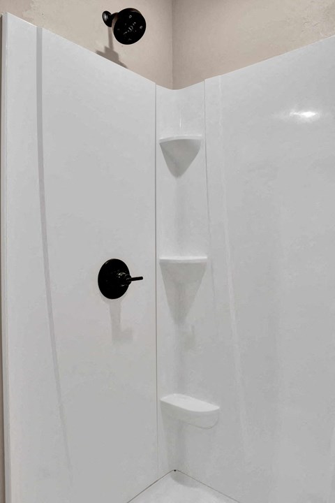 a white shower stall with a black knob in it