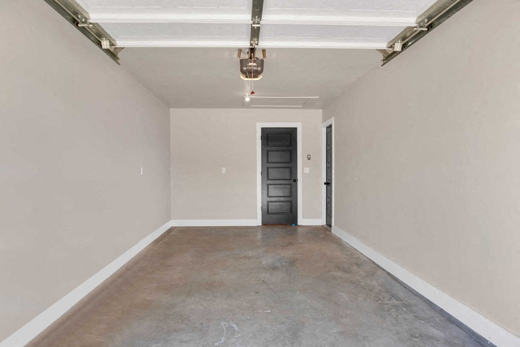 a empty room with a black door and white walls and a concrete floor