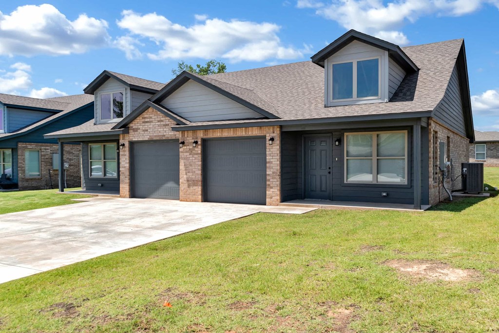 a house with two garage doors and a sidewalk in front of it
