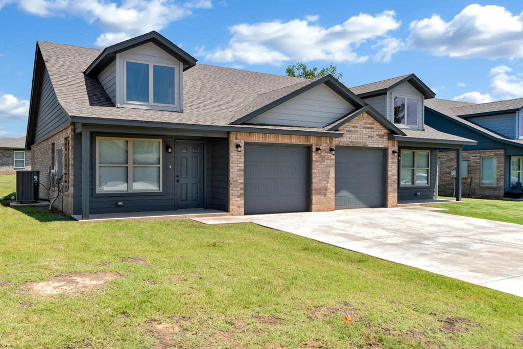 a house with two garage doors and a sidewalk in front of it