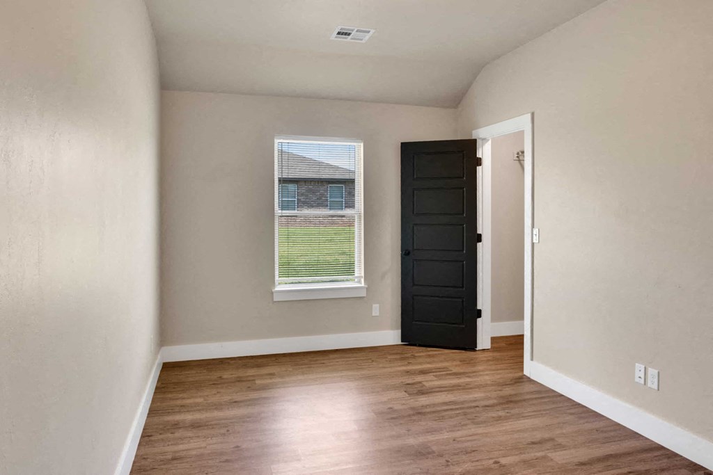 an empty room with a black door and a window