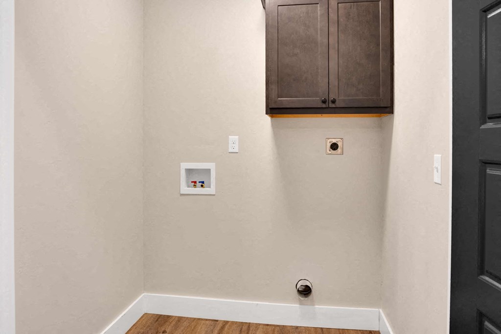 a room with a white wall and a black door and a cabinet