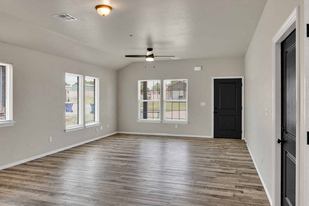 an empty living room with windows and a ceiling fan