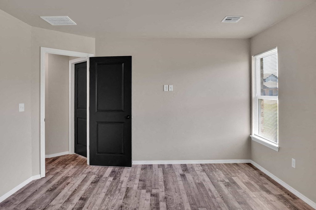 the living room of a home with a black door and wooden floors