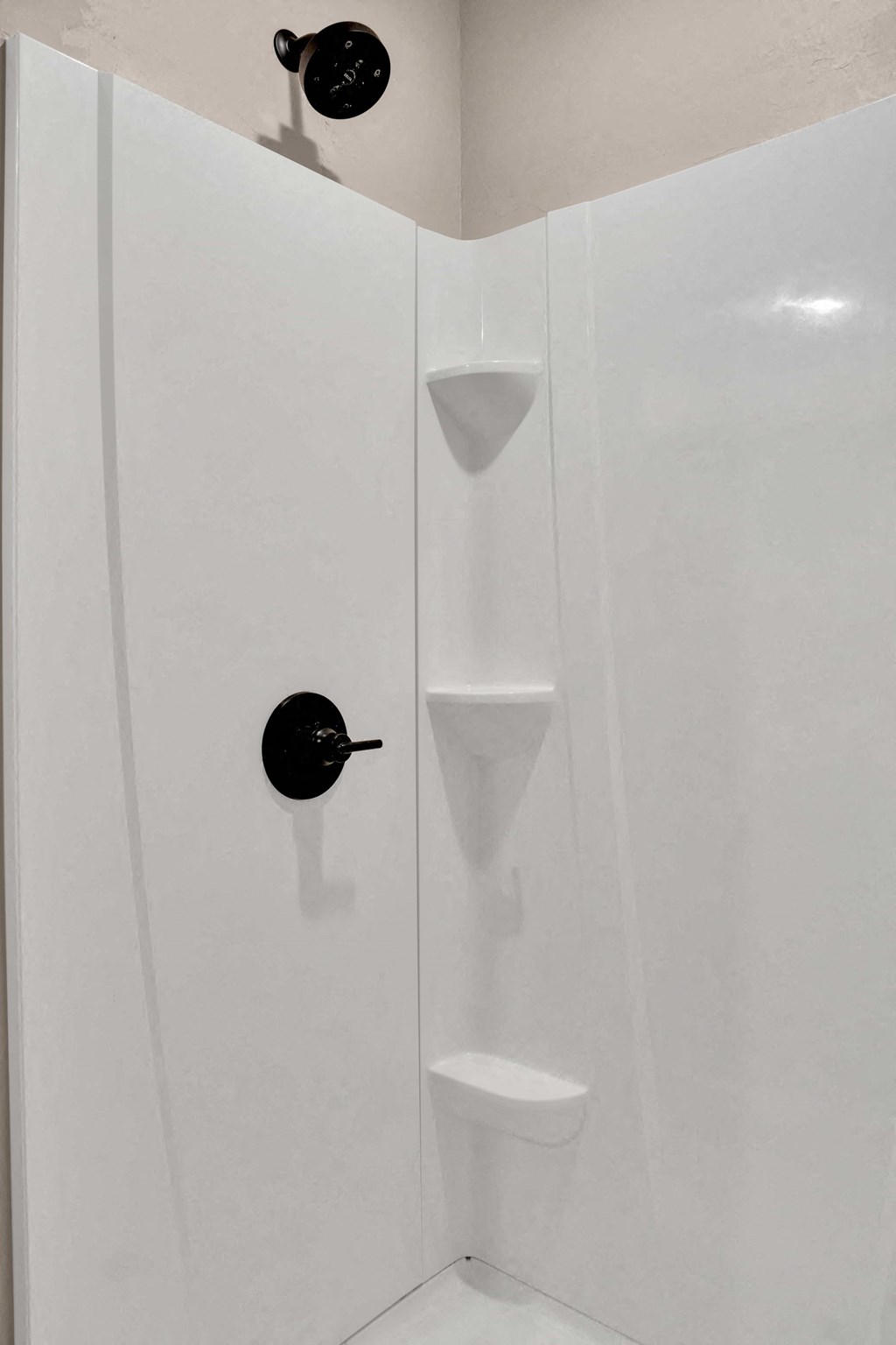 a white shower stall with a black plunger in it
