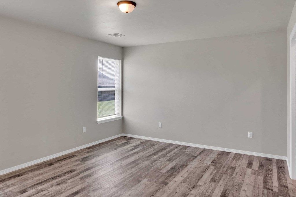 an empty living room with wood floors and a window