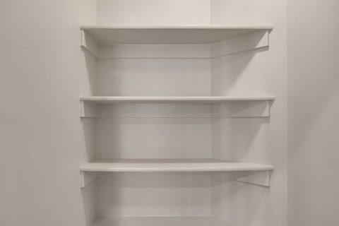 three empty white shelves on a wall in a room