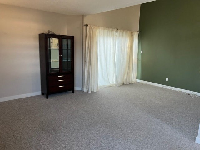 an empty room with a dresser and curtains