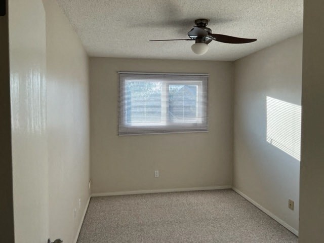 an empty room with a ceiling fan and a window