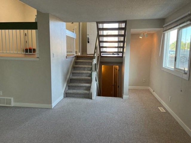 an empty living room with a staircase and a door