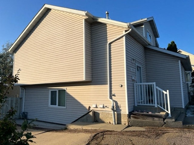 a white house with tan siding and a white staircase