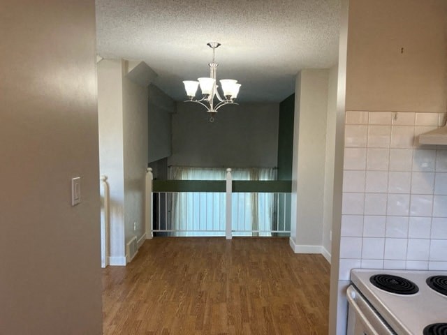 an empty kitchen and living room with a stove and a chandelier