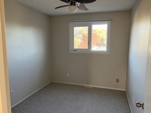 an empty room with a window and a ceiling fan