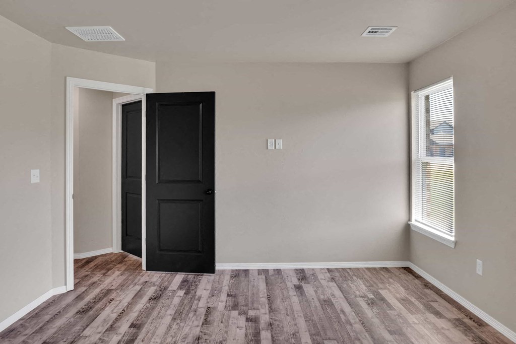 the living room of a home with a black door and wooden floors