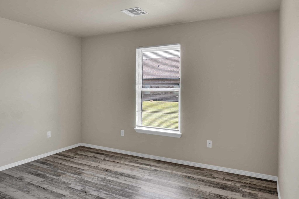 an empty room with wood floors and a window