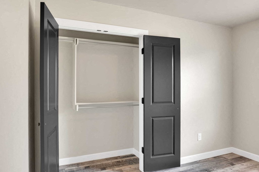 a closet with black doors and white walls and a wood floor