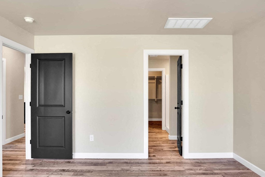 a renovated living room with a black door and a hallway to a closet