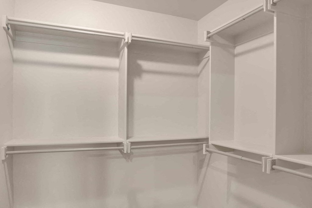 a walk in closet with white walls and white shelving and white cabinets