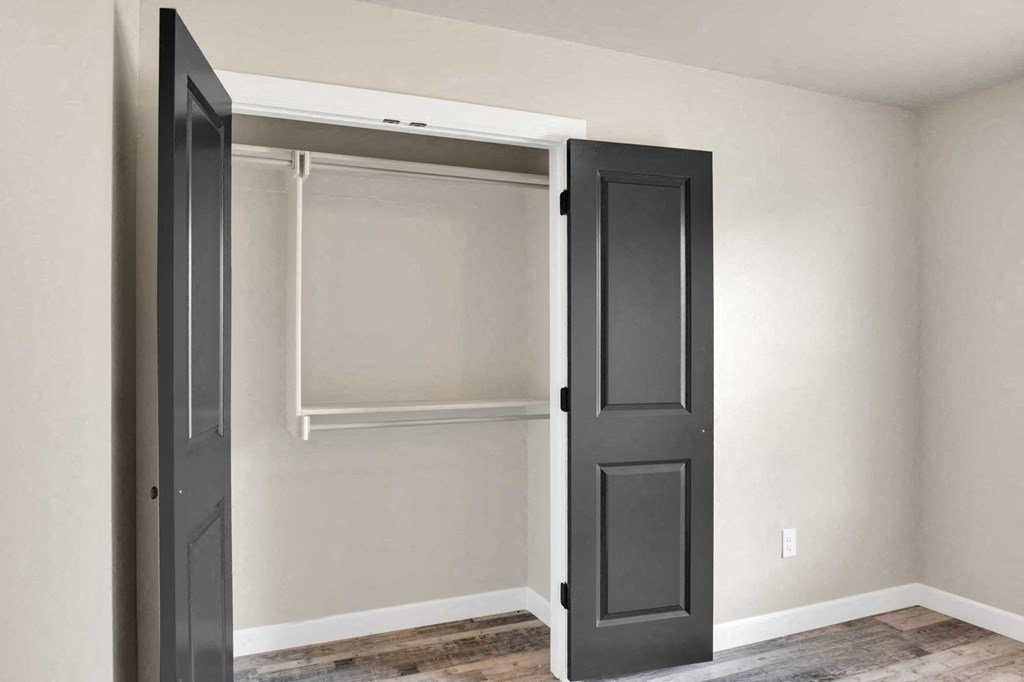 a closet with black doors and white walls and a wood floor