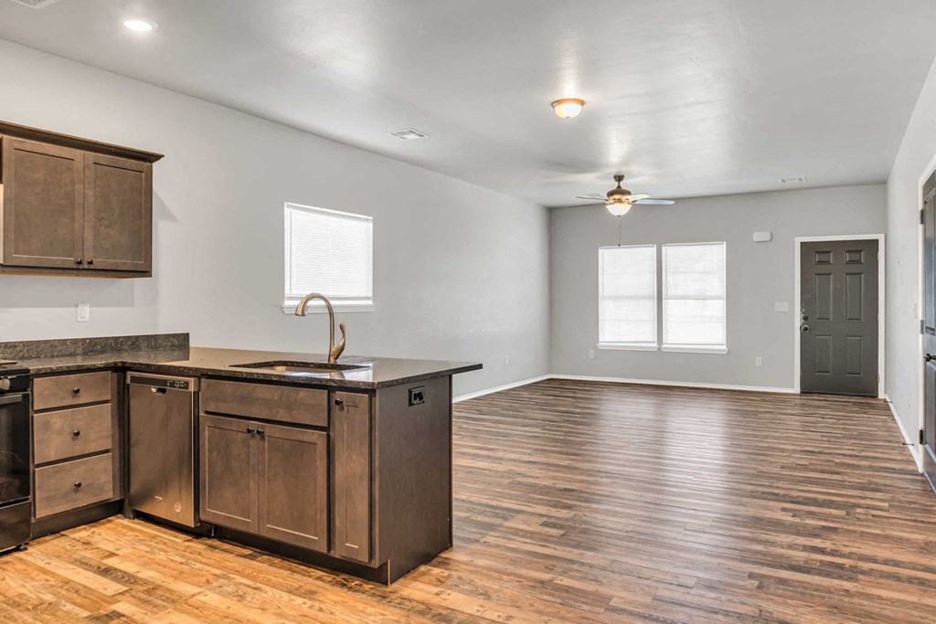an empty kitchen and living room with wooden floors and a counter top