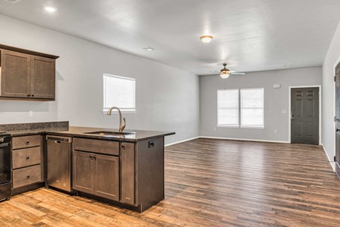 an empty kitchen and living room with wooden floors and a counter top