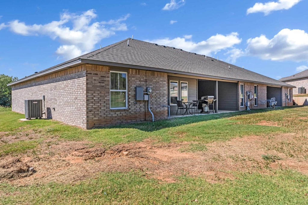 the front of a brick house with a yard and a patio