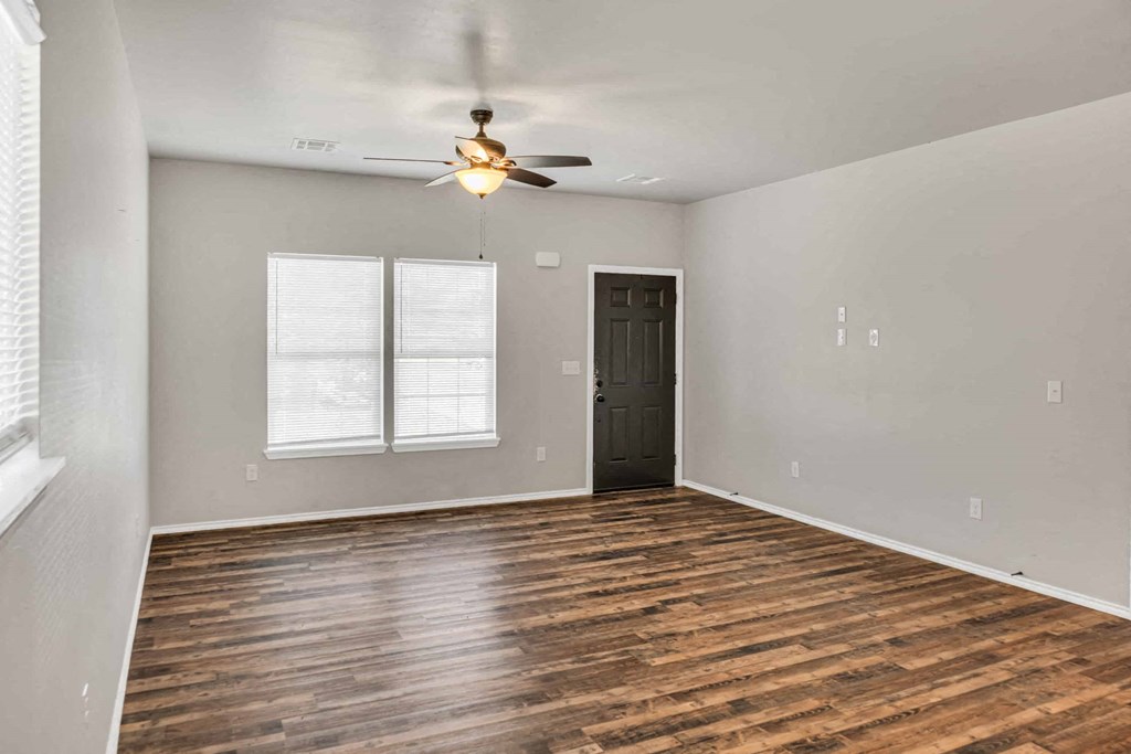 an empty living room with a ceiling fan and a window