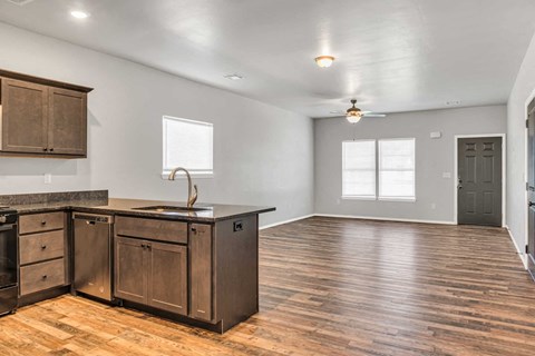 an empty kitchen and living room with wooden floors and a counter top