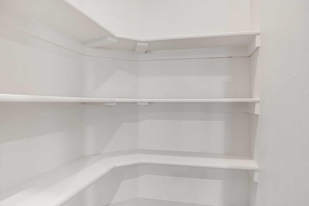 an empty closet with white shelves in a white room