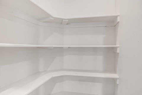 an empty closet with white shelves in a white room
