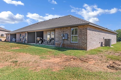 the front of a brick house with a yard and a patio