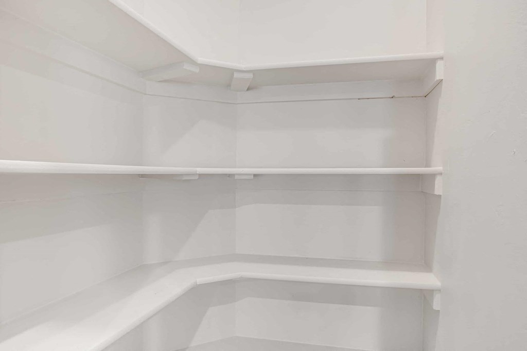 an empty closet with white shelving and white walls