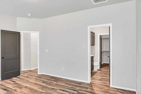 a renovated living room with a wooden floor and a door into a hallway