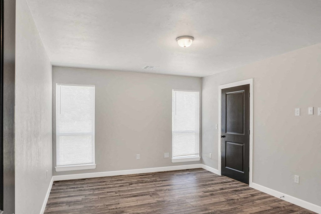 an empty living room with a black door and white walls