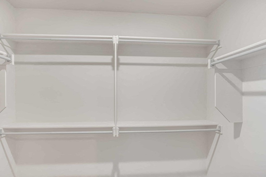 a walk in closet with white walls and a white closet organizer