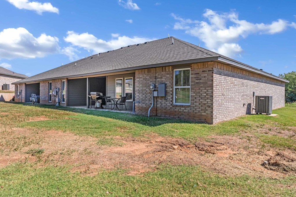 the front of a brick house with a yard and a patio