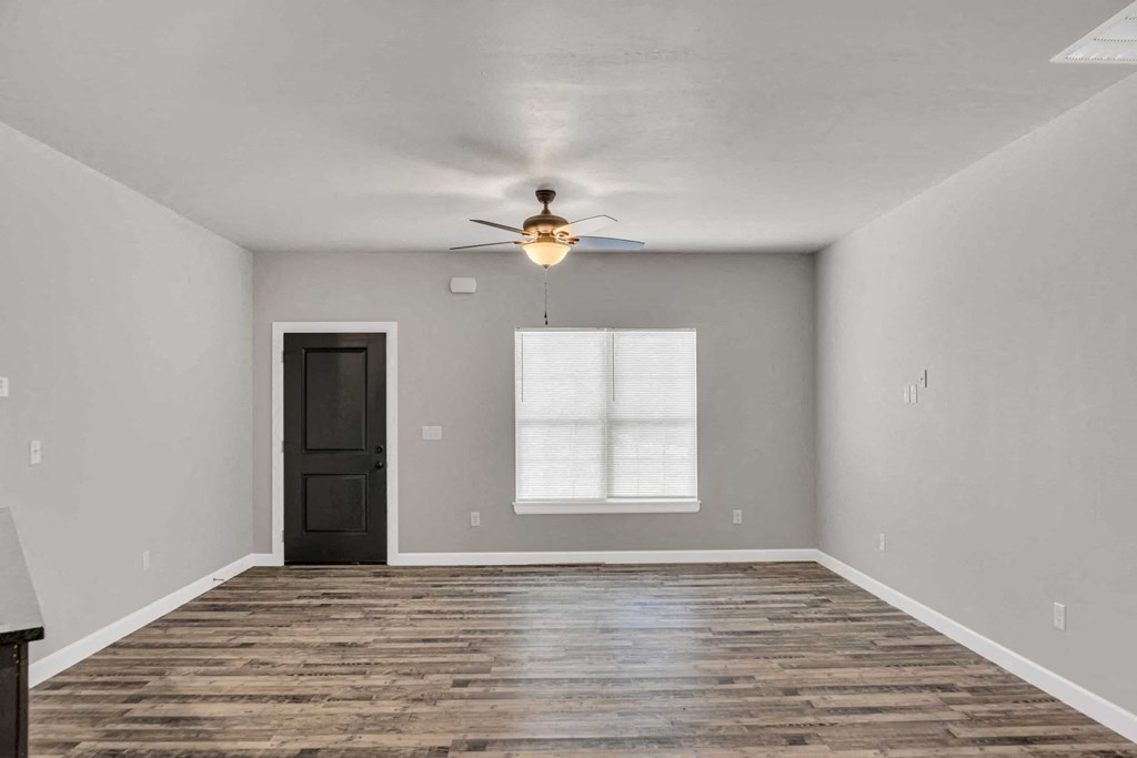 an empty living room with a ceiling fan and a window